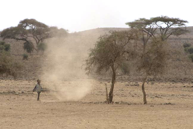 Masai child playing tag with dust devil, Amboseli Kenya
